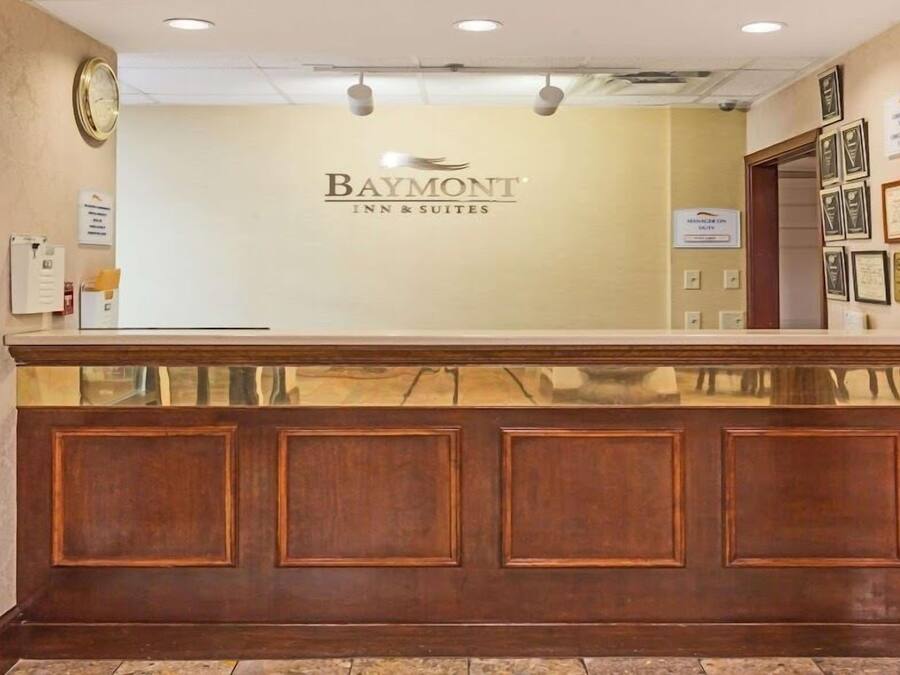 A reception desk with a wooden panel design, a clock, and framed certificates on the wall.