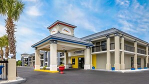 A hotel with a covered entrance, a sign for 'Baymont,' and a palm tree in the foreground.
