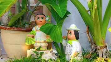 Two ceramic figures, one holding a plant, and a potted plant with large leaves in the background.