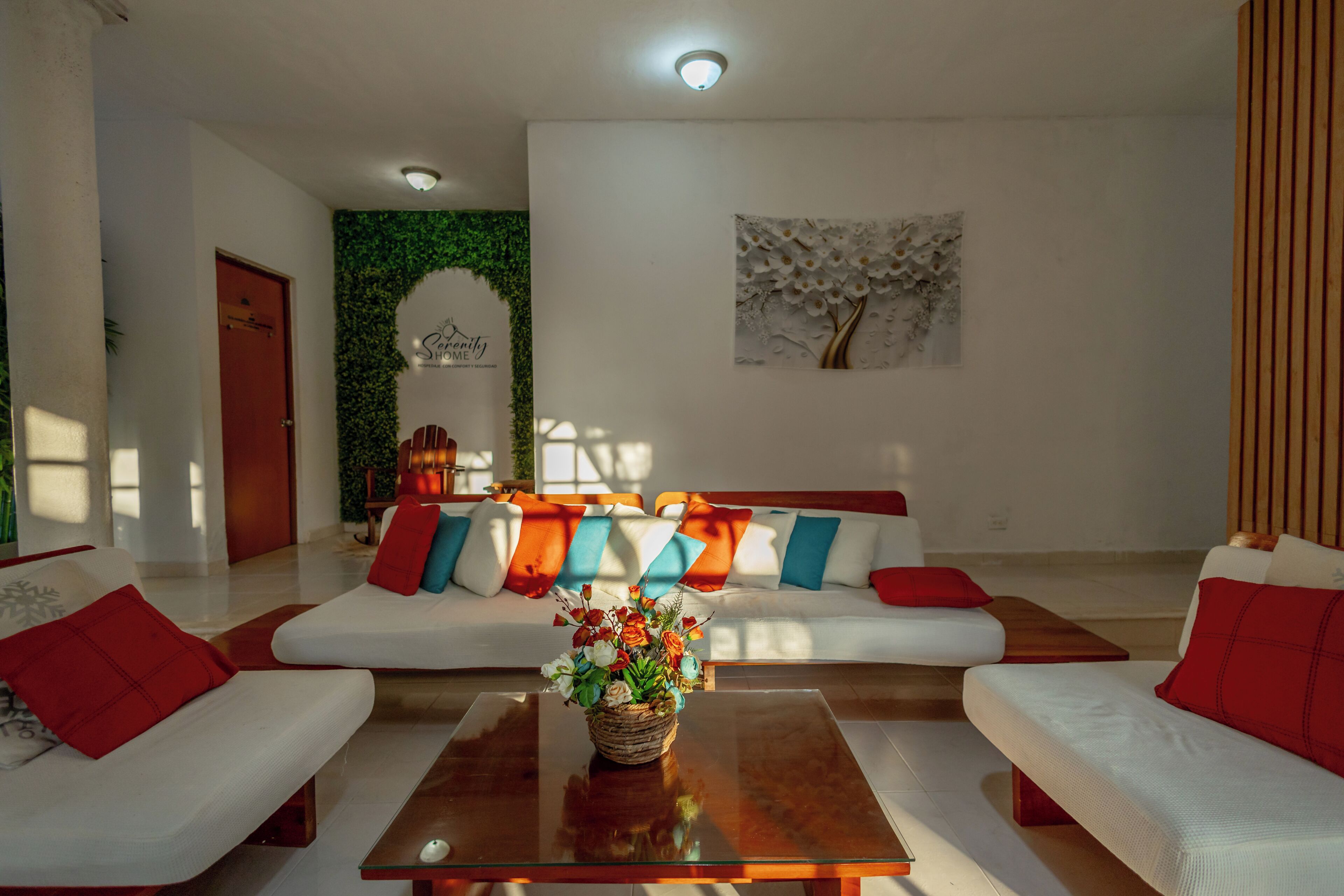 Una sala moderna con un conjunto de sofás, una mesa de centro y una pared con un arco verde y una pintura de un árbol.