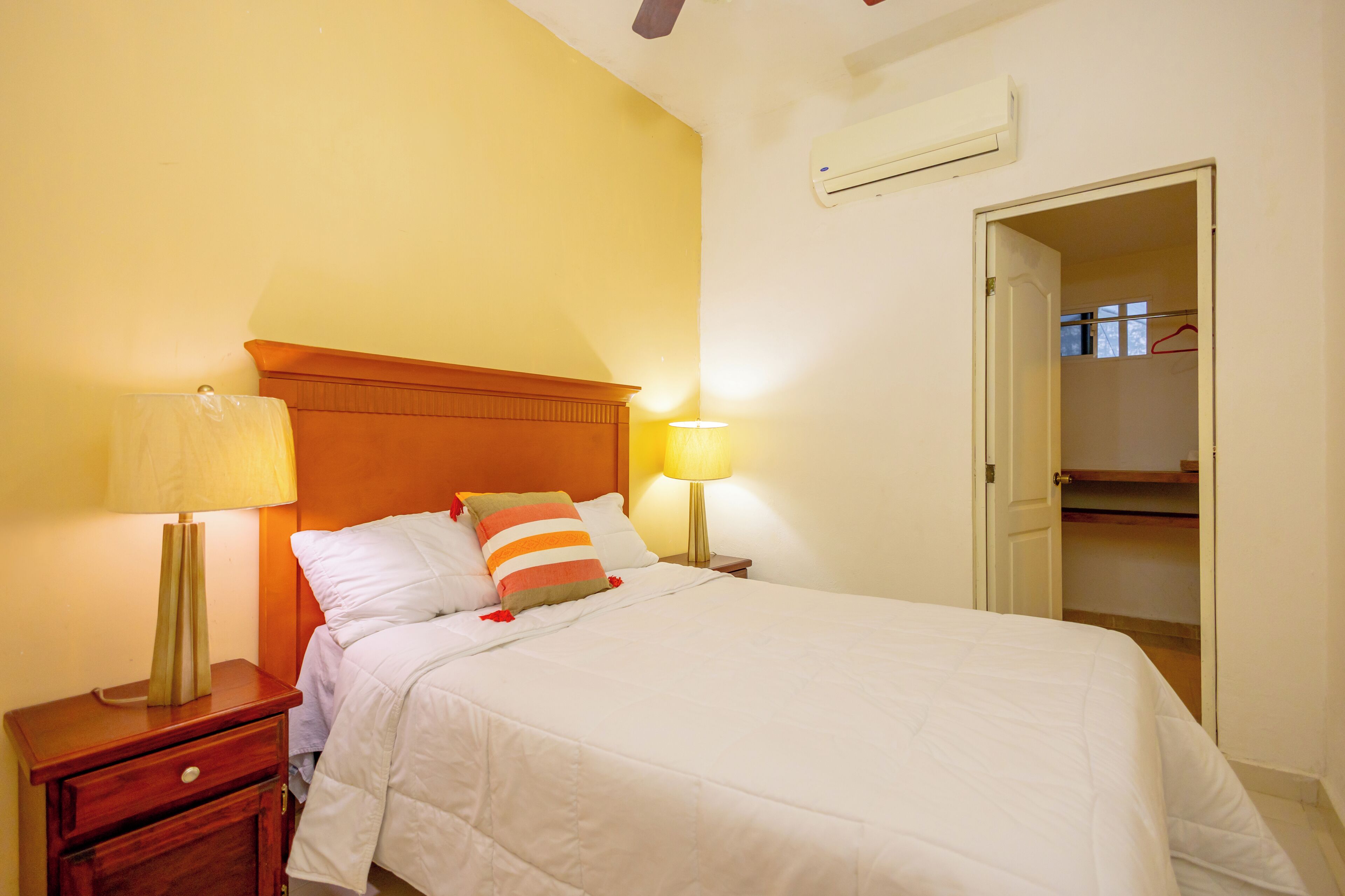 A neatly made bed with white bedding, a wooden headboard, and two bedside lamps.