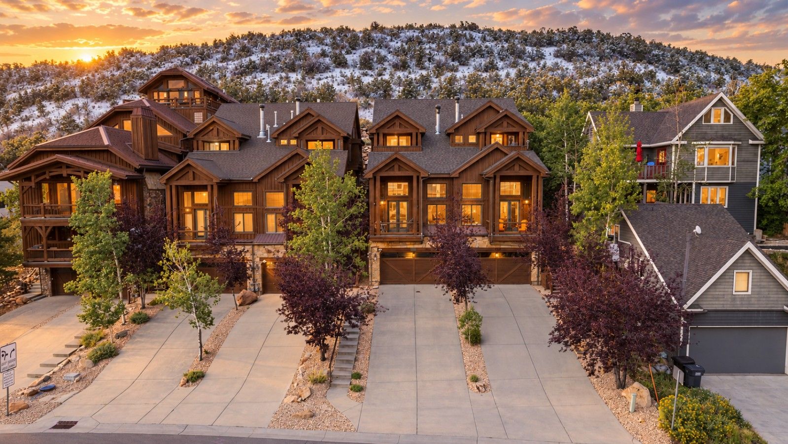 A multi-story residential building with a symmetrical facade, large windows, and a driveway leading to a garage.