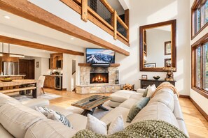 A spacious living room with a stone fireplace, a large flat-screen TV, and a cozy seating area.