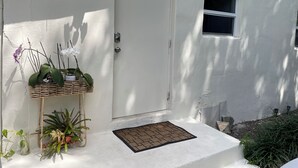 A white door with a security camera, a small window, and a welcome mat.