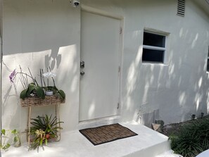 A white door with a security camera, a small window, and a welcome mat.
