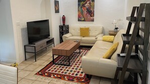 A living room with a TV, sofa, coffee table, patterned rug, and artwork on the wall.