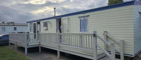 Une maison mobile dotée d’une véranda, d’une cheminée et d’un garage.