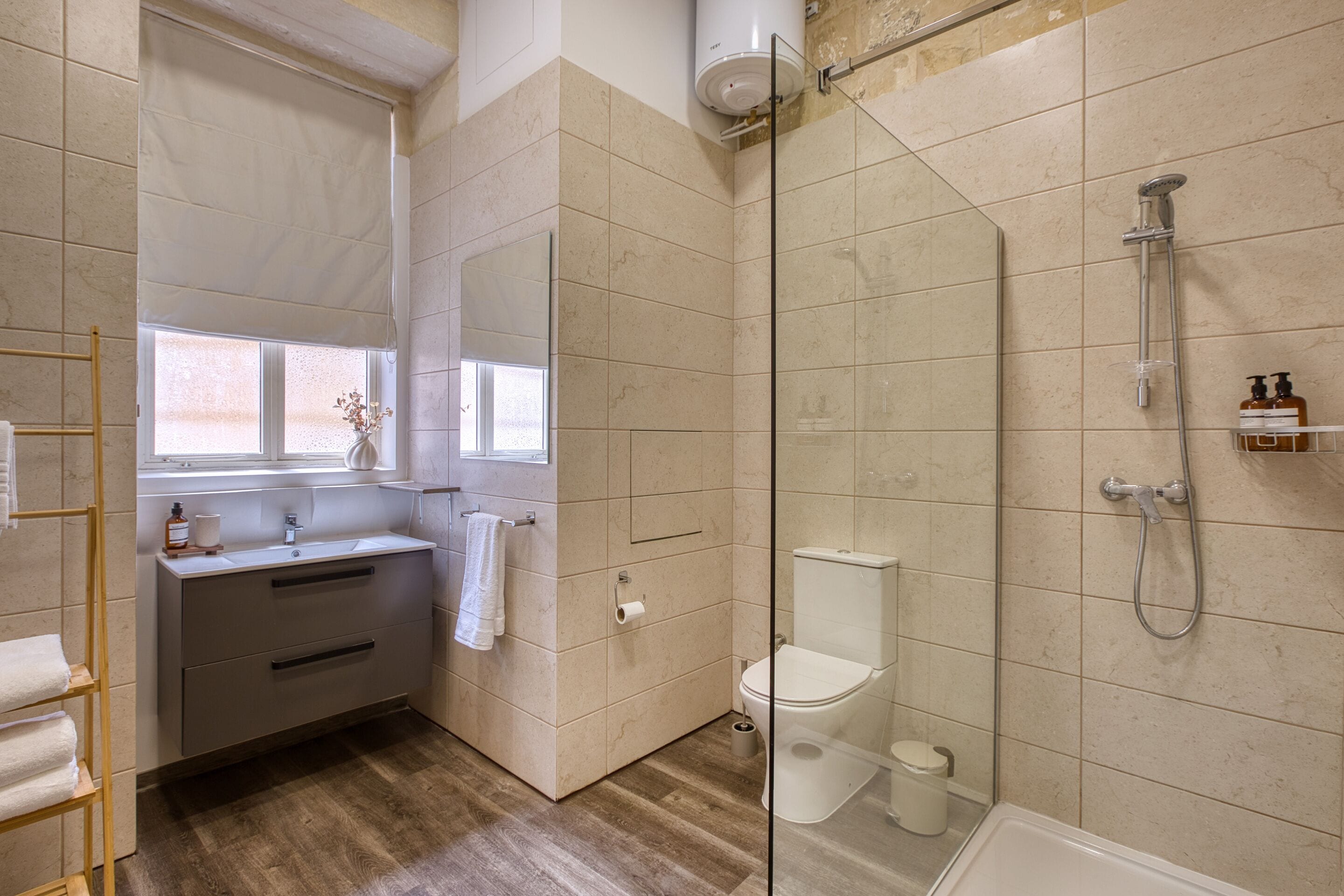 Et moderne badeværelse med en glasbrusekabine, toilet og håndvask med håndklædestang.