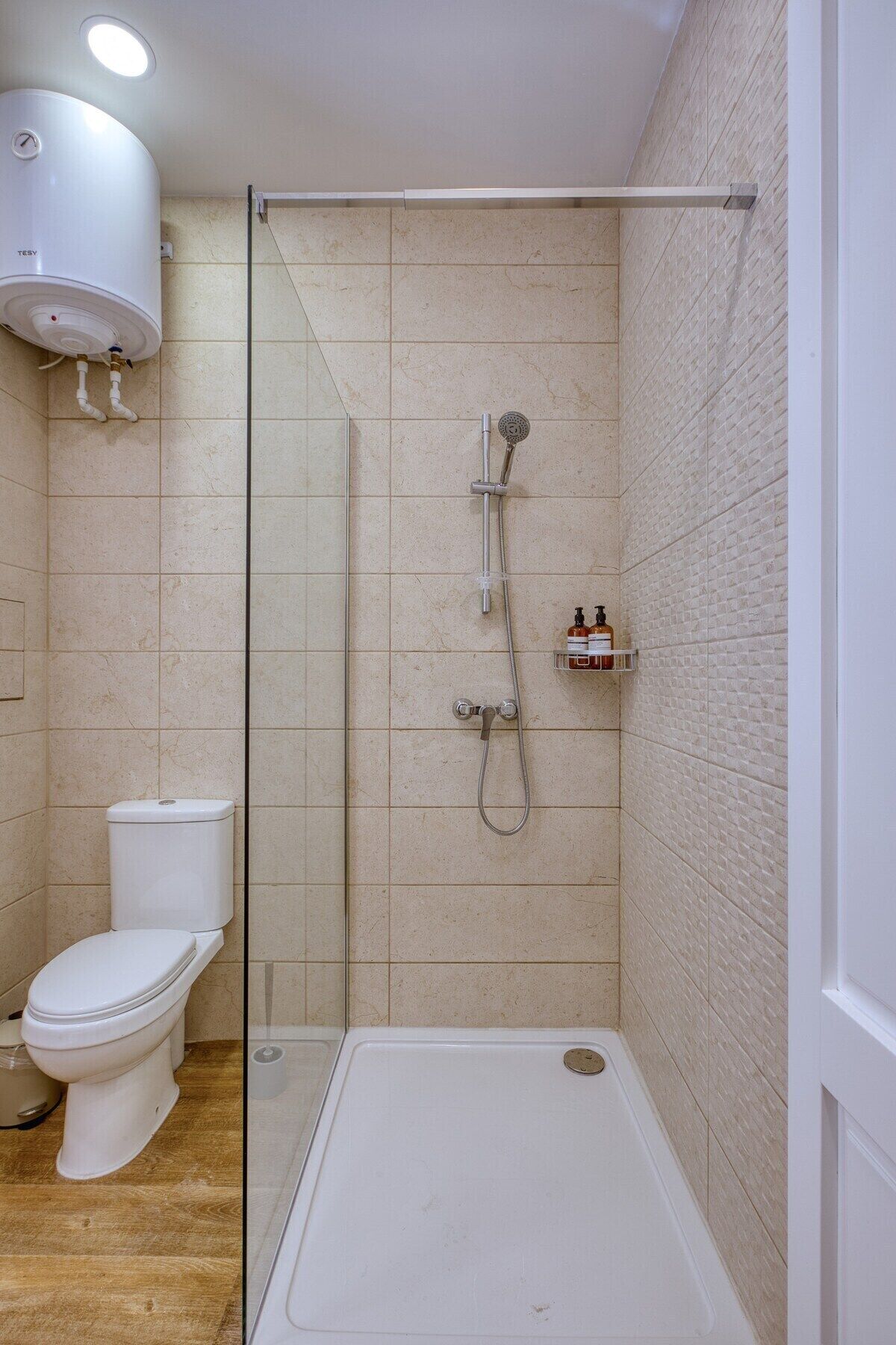 A bathroom with a toilet, a shower enclosure, and a white bathtub.