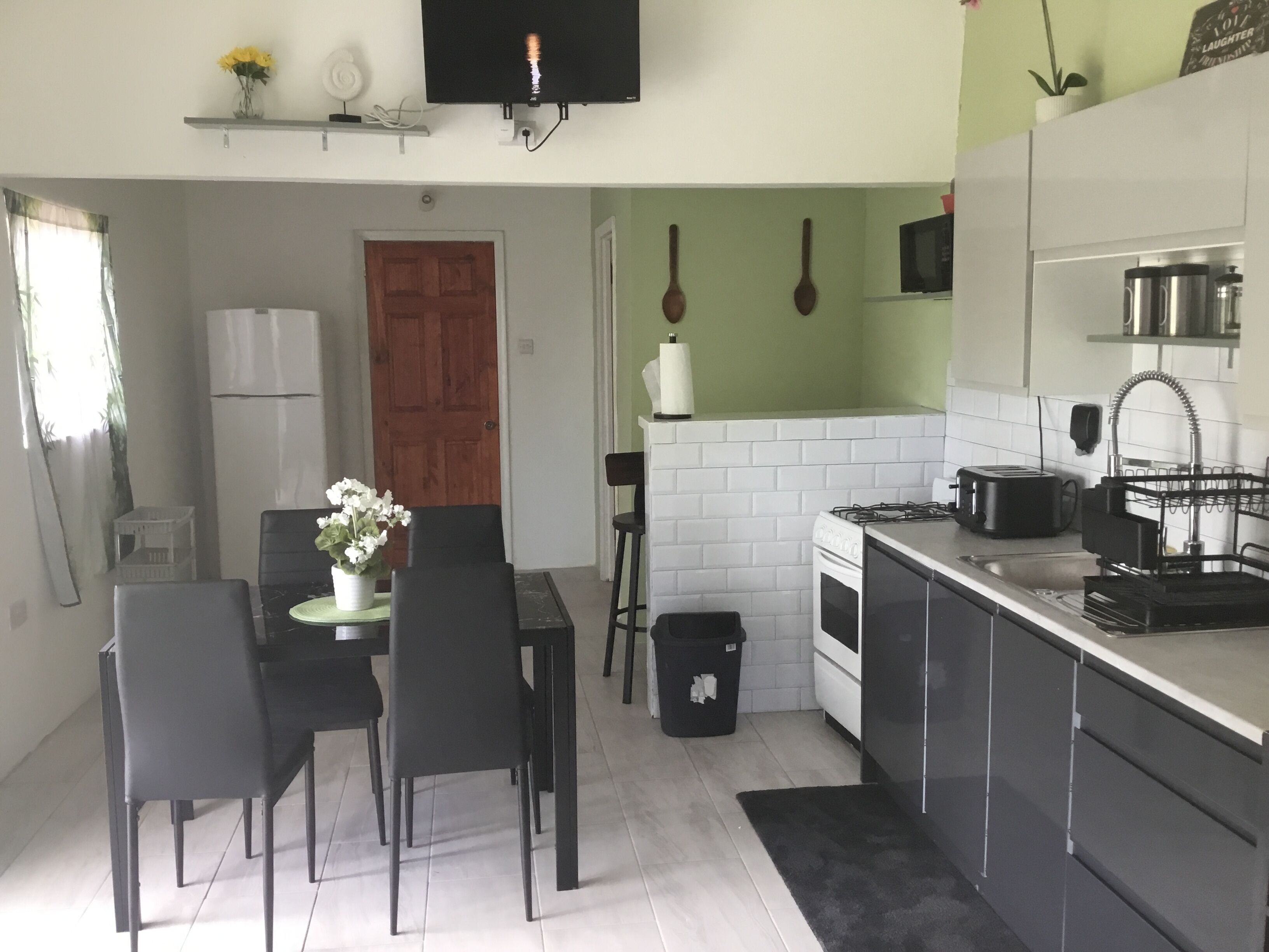 A compact kitchen with a dining area, a stove, a microwave, and a sink.