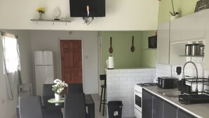 Een kleine keuken met een eethoek, een fornuis, een magnetron en een spoelbak.