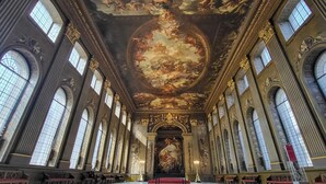 A grand hall with high ceilings, ornate ceiling artwork, and tall windows.