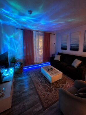 A living room with a sofa, a coffee table, a TV, and a window with curtains.