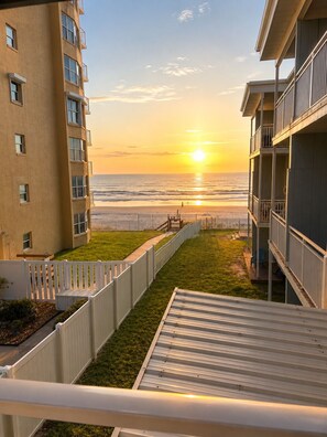 A view of a balcony overlooking a beach with a sunset.