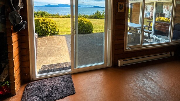 Habitación con techo de madera, puerta corrediza de vidrio que da a un patio y una pequeña alfombra en el suelo.