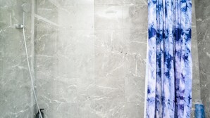 A bathroom with a shower, a glass door, and a blue and white patterned curtain. - Joyden's Wood 2-bed Apt, Sleeps 5 With Parking (Dartford)