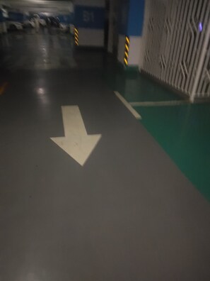 Eine Parkgarage mit Pfeilen auf dem Boden, einer blauen Wand mit einem Schild und einer Wand mit Muster rechts.