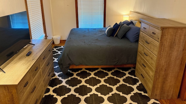 A bedroom with a bed, dresser, TV, and windows with blinds. - Cozy 1-bedroom apartment in nice Brownwood with AC (Brownwood)