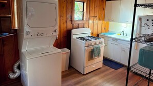 A compact kitchen with wooden walls, a gas stove, a built-in oven, a washing machine, and a refrigerator. - Cozy 1-bedroom apartment in nice Brownwood with AC (Brownwood)