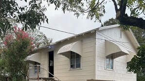 A two-story house with a porch, a small staircase, and a garage. - Cozy 1-bedroom apartment in nice Brownwood with AC (Brownwood)