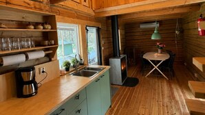 A wooden cabin interior with a kitchen, dining area, and a fireplace. - Cabin in the Woods (Malung)