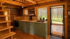 A cabin interior with a wooden interior, a kitchen area, and a door leading outside. - Cabin in the Woods (Malung)