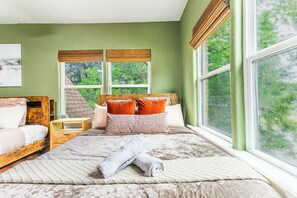 Ein Schlafzimmer mit einem großen Bett, zwei Nachttischen, einem Fenster mit Blick ins Grüne und einem Bild an der Wand.