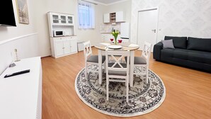A modern living room with a dining area, a black sofa, a chandelier, and a kitchen in the background. - Sophia Neighborhood - Spacious 92-square-meter basement apartment near Goethepark (Weimar)