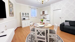 A modern living room with a dining area, white cabinetry, a flat-screen TV, and a chandelier. - Sophia Neighborhood - Spacious 92-square-meter basement apartment near Goethepark (Weimar)