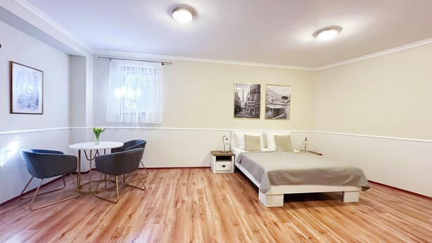 A bedroom with a bed, bedside table, lamp, chair, and a small table with a vase. - Sophia Neighborhood - Spacious 92-square-meter basement apartment near Goethepark (Weimar)