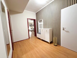 A hallway with wooden flooring, a white wardrobe, and a mirrored closet door. - Sophia Neighborhood - Spacious 92-square-meter basement apartment near Goethepark (Weimar)