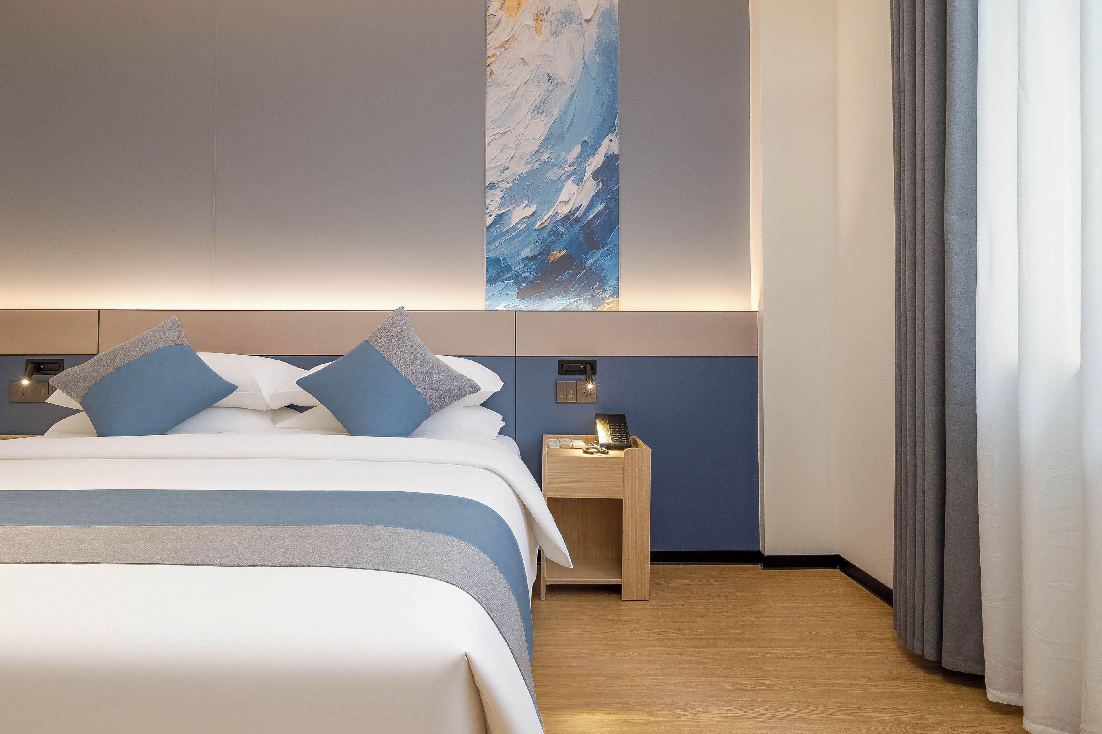 Habitación de hotel con cama, mesita de noche y teléfono en la pared.