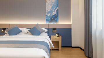 Habitación de hotel con cama, mesita de noche y teléfono en la pared.