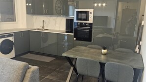 A modern kitchen with a built-in oven, microwave, and a dining area with a table and chairs. - The Cosy4 at Disneyland & Paris (Noisy-le-Grand)
