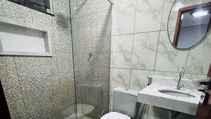A bathroom with a glass-enclosed shower, a toilet, a sink, and a mirror. - Two-room suite equipped with air conditioning in the center of Arraial do Cabo, RJ. (Arraial do Cabo)