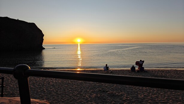 A beach scene with a sunset, calm sea, and a cliff. - 2 Mins Walk to Beach - Pet-Friendly - Cosy Cottage Llangrannog (Llangrannog)