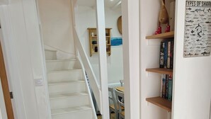 A staircase leading to a dining area with a wooden floor and a wall with a poster. - 2 Mins Walk to Beach - Pet-Friendly - Cosy Cottage Llangrannog (Llangrannog)