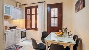 Una cucina compatta con zona pranzo, completa di piano cottura, pensili e tavolo con sedie.