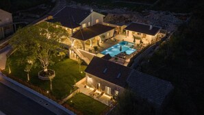 A residential property with a swimming pool, multiple buildings, and a well-lit garden. - Luxury villa Speranza with heated saltwater pool (VINJANI DONJI,IMOTSKI)