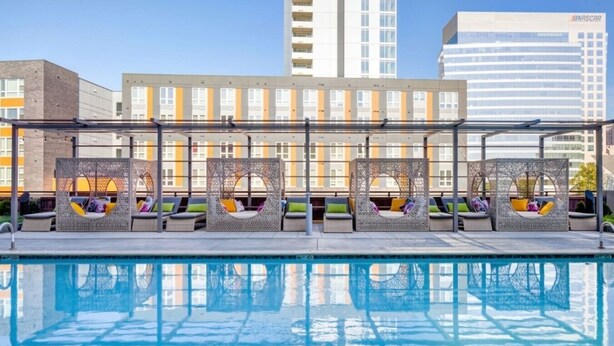 Zona junto a la piscina con sillones de descanso y vista a un edificio moderno.