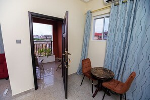 A room with a balcony, a round table with chairs, and a window with curtains. - Luxury 1 and 2 bedrooms house in nice Braives with cool AC (Braives)