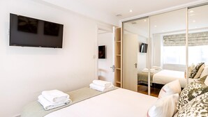 Ein Hotelzimmer mit Bett, Wandfernseher, Kleiderschrank und Spiegel.