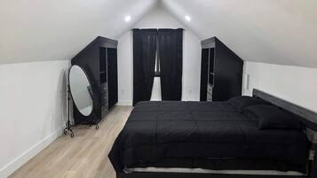 A bedroom with a bed, a vanity with a mirror, and a wardrobe.