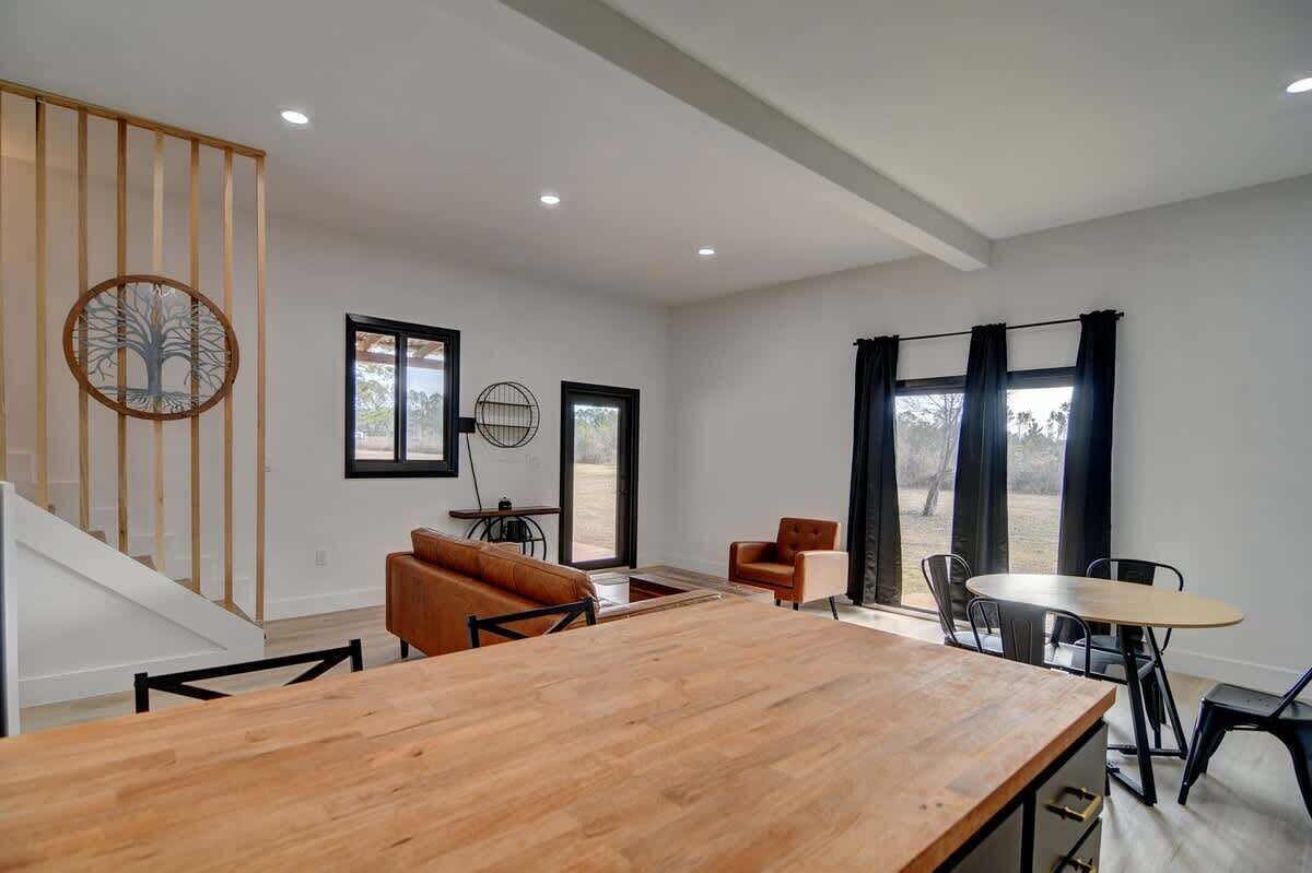 A spacious room with a wooden dining table, a sofa, and a staircase.