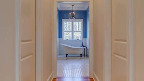 A hallway with wooden flooring, white walls, and a window with a view.