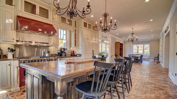 A spacious kitchen with a large island, stainless steel appliances, and a chandelier.