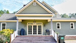 A two-story house with a front porch, a garage door, and a trash bin.