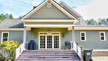 A two-story house with a front porch, a garage door, and a trash bin.