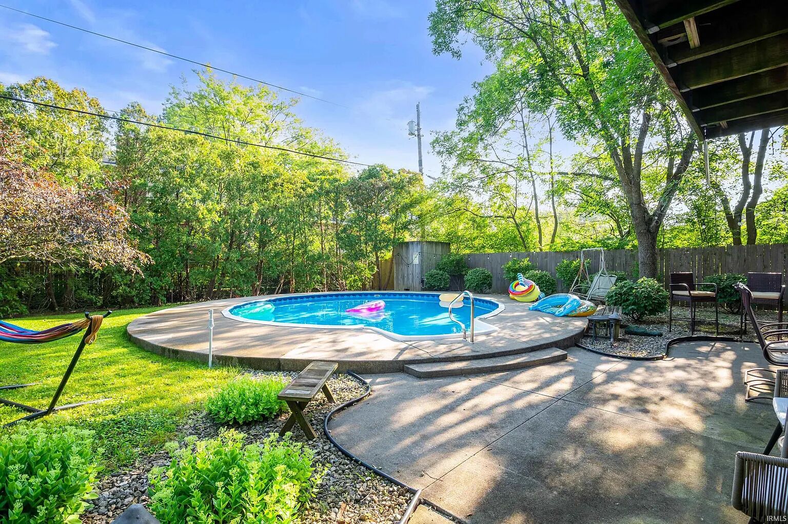 Ein Garten mit Swimmingpool, Hängematte und Gartenmöbeln.