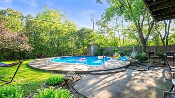 Ein Garten mit Swimmingpool, Hängematte und Gartenmöbeln.